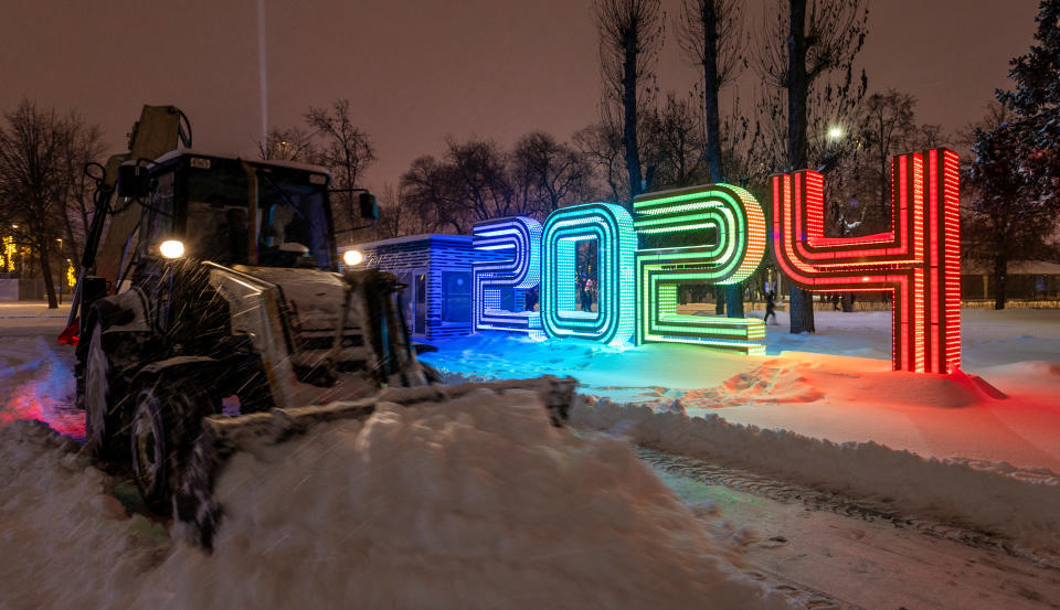 2023 年 12 月 3 日，俄罗斯莫斯科，在一场大雪中，一辆拖拉机在庆祝 2024 年新年的装饰品旁边清理积雪。 REUTERS/Maxim Shemetov