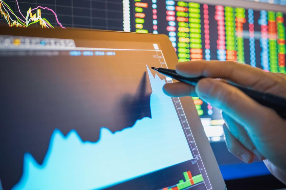 股票交易员使用手写笔与平板电脑上显示的快速上涨的股票图表进行交互。